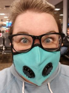a girl wearing black glasses and a blue face mask that covers her nose and mouth