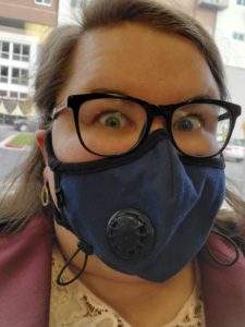a girl wearing black glasses and a blue face mask that covers her nose and mouth to protect against fragrance allergy and sensitivity